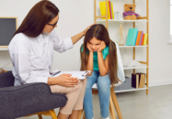 Frau und Mädchen sitzen in einem Gesprächsraum, Mädchen hält sich Hände vor das Gesicht