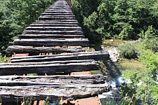 Hängebrücke aus Holzbohlen ohne Geländer über dem Abgrund